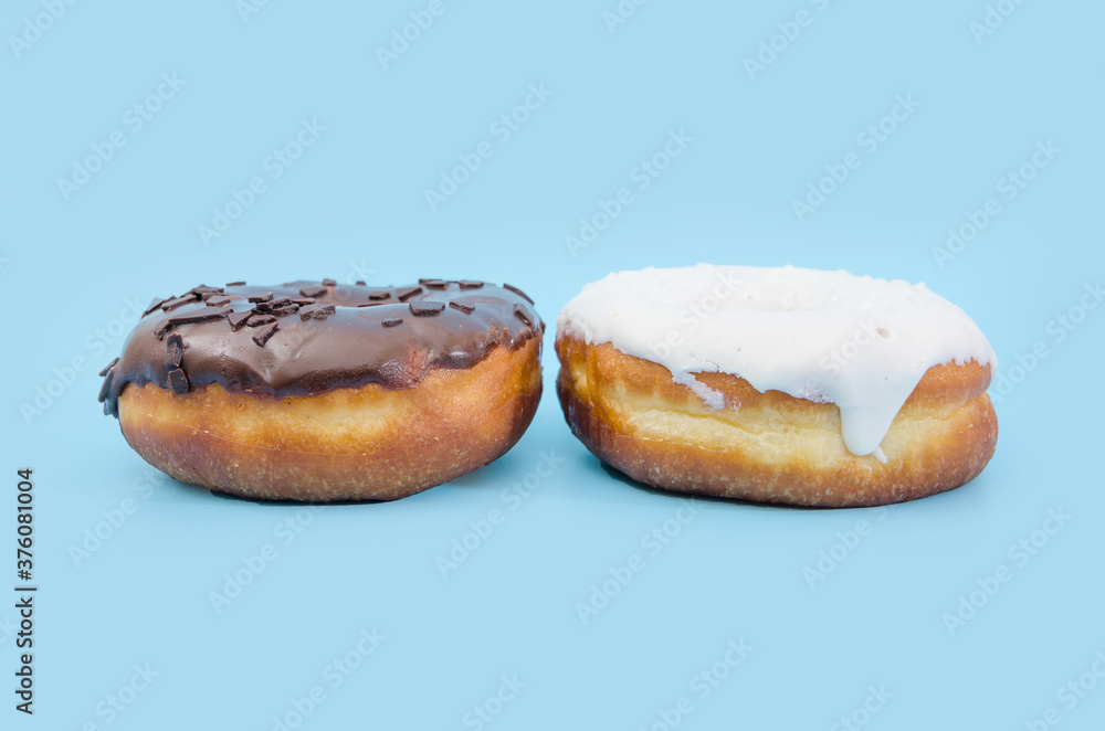 Two delicious donuts with black and white chocolate icing isolated on a blue background.