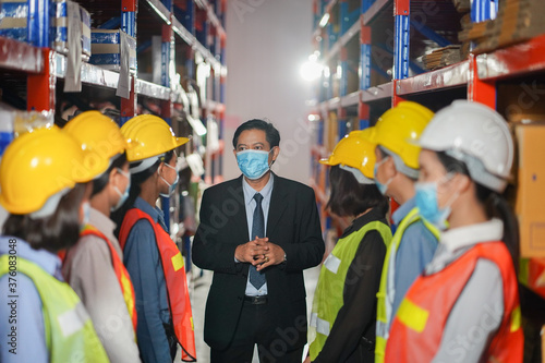Manager teching a mask. Manager with worker team working warehouse. During working hours in the warehouse, checking, stock for quality products, people worker in warehouse concept.