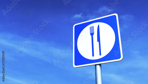 Road sign "Food point" on a metal pole against the blue sky