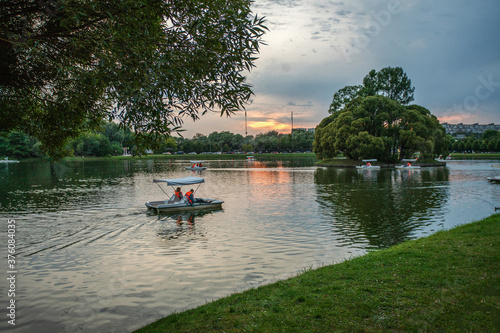 People sail on a catamaran in the park's pond, rented