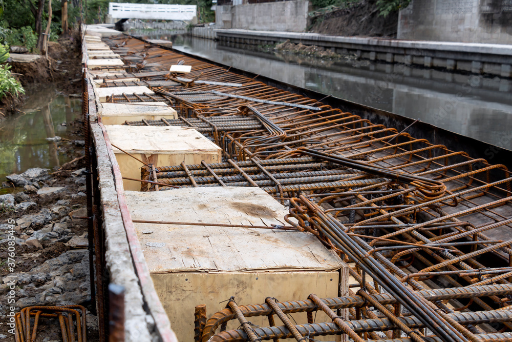 Steel reinforcing tie wire work at construction site of embankment for canal path and protecting riverbank collapse structures. rebar bars reinforcement for reinforced concrete. Steel reinforcing tie wire work at construction site of embankment for canal path and protecting riverbank collapse structures. rebar bars reinforcement for reinforced concrete.