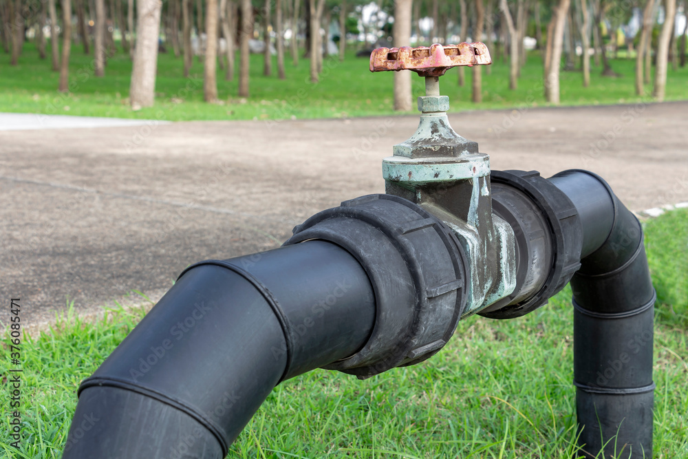 Black water pipes joined with rusty red valves for safety and clean
