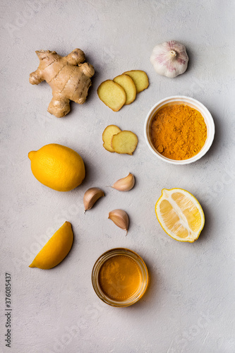 Turmeric, ginger, honey, garlic, lemon ingridients for making drinks. Folk remedies top view on gray background to prevent and treat colds, support the immune system and immune booster
