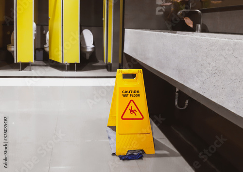 Sign yellow slippery warning floor wet, caution for toilet room cleaning progress. Safety sign with text caution. © nicemyphoto
