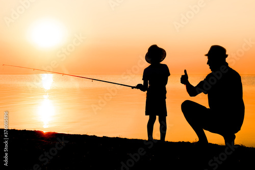 Photography A Happy father and child fishermen catch fish by the sea on nature silhouette tr