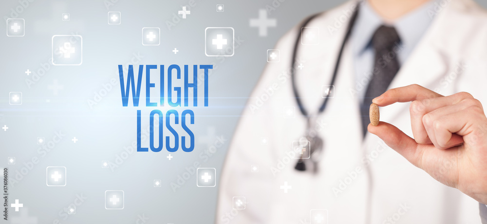 Close-up of a doctor giving a pill with WEIGHT LOSS inscription, medical concept Close-up of a doctor giving a pill with WEIGHT LOSS inscription, medical concept