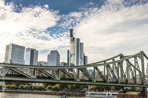 Frankfurt / Main, Germany - September 03rd 2020: A german photographer visiting the "Eiserner Steg" at a sunny day. View along the river Main to the skyline of the financial district Frankfurt.