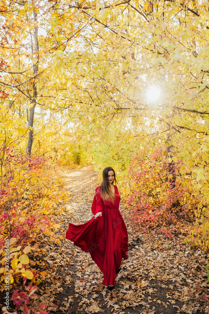 Naklejka premium Beautiful girl walking outdoors in autumn colorful forest. Young girl enjoying autumn weather.