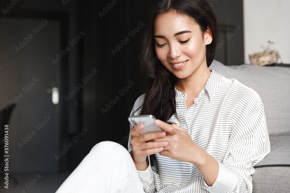 Portrait of young beautiful asian girl texting message on smartphone. Woman resting at home and browsing social networks on mobile phone. Female shopping online, using application Portrait of young beautiful asian girl texting message on smartphone. Woman resting at home and browsing social networks on mobile phone. Female shopping online, using application
