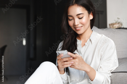 Tela Portrait of young beautiful asian girl texting message on smartphone