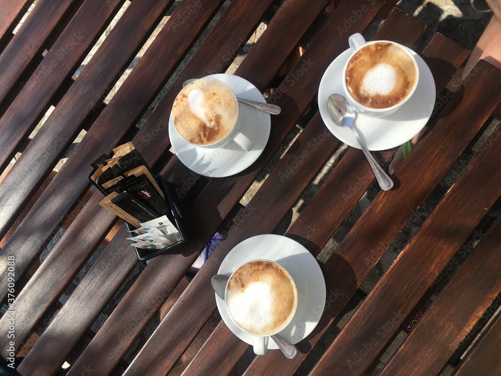 Wooden table in cafe with three cups of cappuccino
