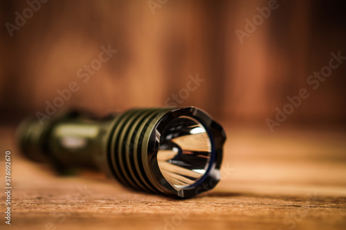 Detail close up of flashlight on a blurred wooden background. 