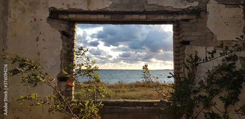 View of the sea in cloudy day through the wall of the destroyed building