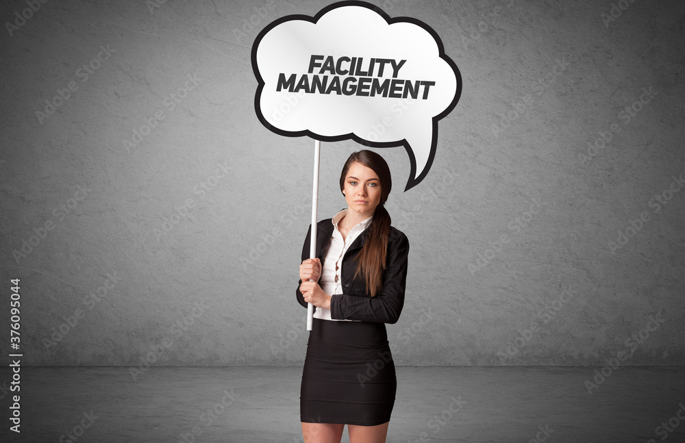 Young business person in casual holding road sign with FACILITY MANAGEMENT inscription, new business idea concept Young business person in casual holding road sign with FACILITY MANAGEMENT inscription, new business idea concept