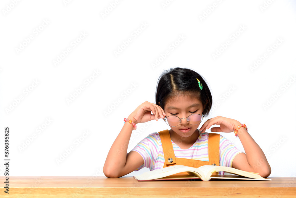 Asian female kid who wear glasses while concentrate reading a textbook