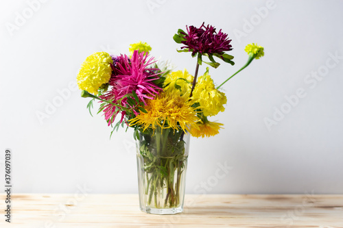 Autumn bright shaggy flowers bouquet in vase on wooden table