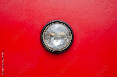 Retro round headlight on red background.