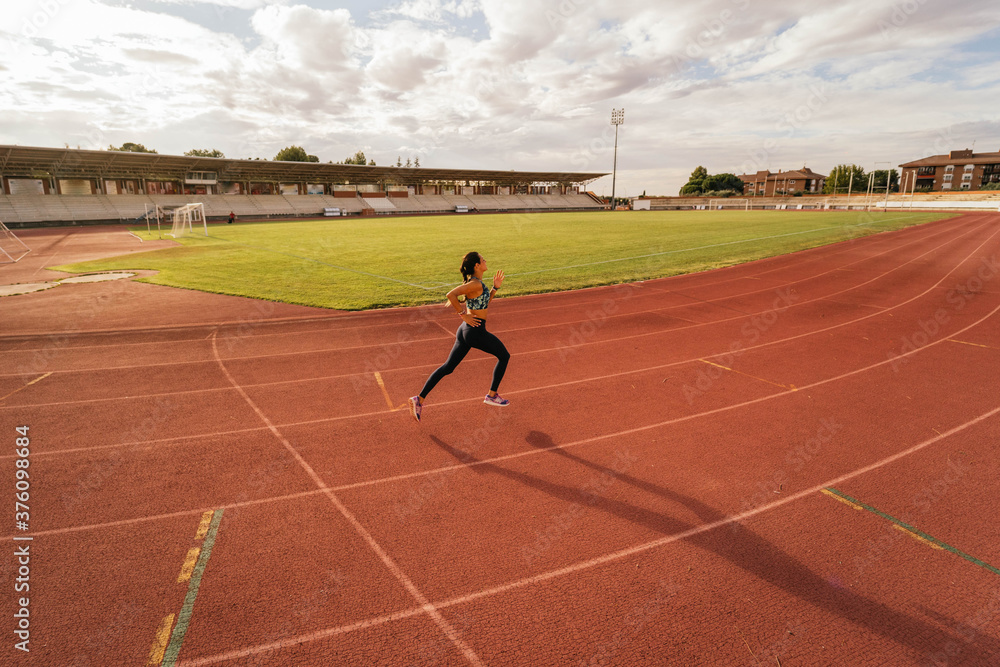 Fototapeta premium Young girl running on running track