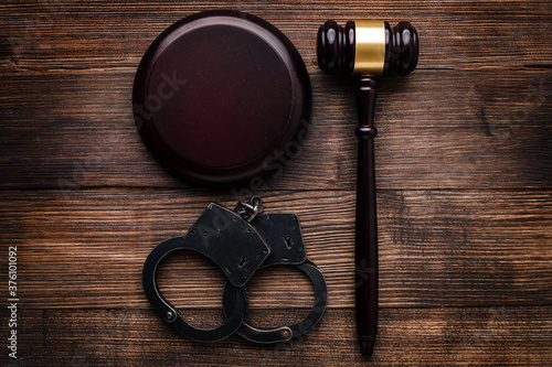 Arrest concept. Handcuffs near judge gavel on dark wooden background