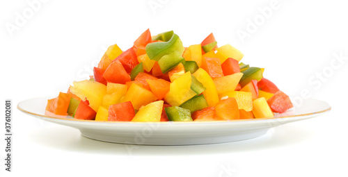 Yellow, red and green peppers Bulgarian. Slicing. Cubes in plate on white