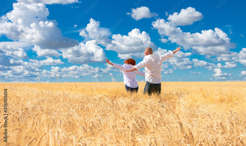 A young couple, a man and a woman in white shirts, run across a Golden wheat field, arms outstretched, miming flight. A man and a woman run into the field, rejoicing and enjoying life. A young couple, a man and a woman in white shirts, run across a Golden wheat field, arms outstretched, miming flight. A man and a woman run into the field, rejoicing and enjoying life.