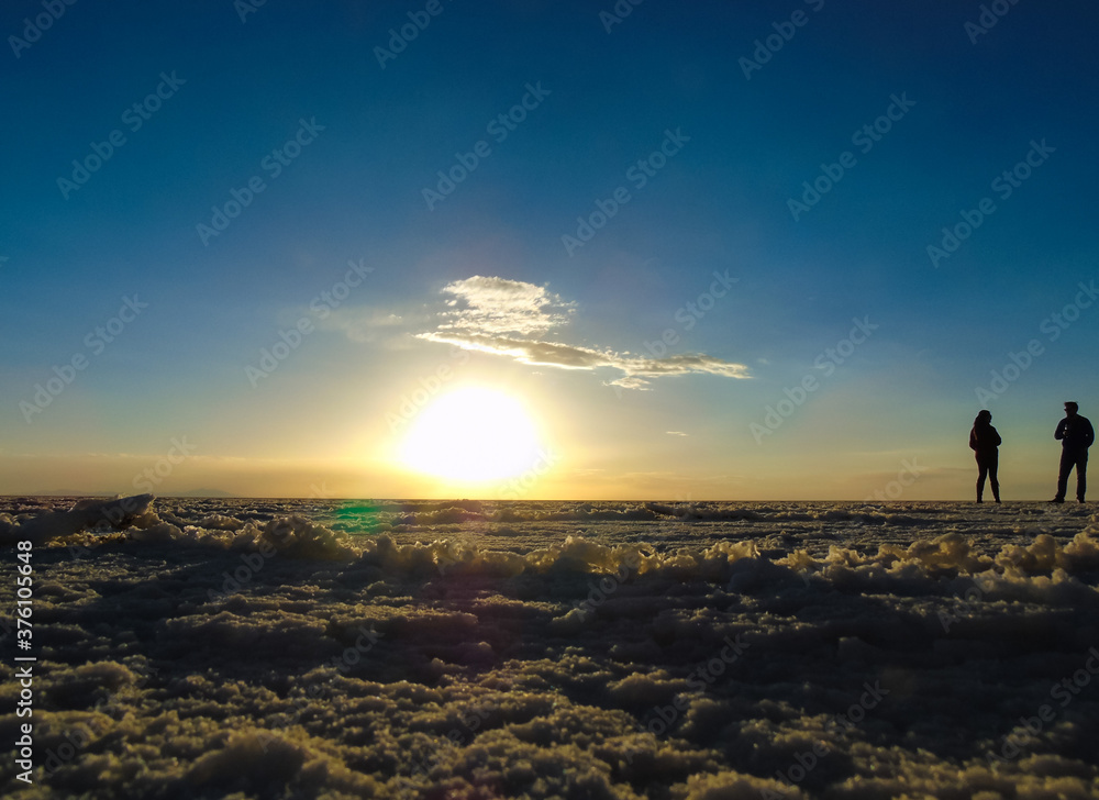 A couple is enjoying the beautiful sunset at Uyuni Salt Flat