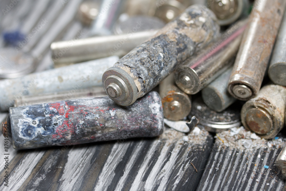 Corroded used batteries. On pine boards. Disposal of hazardous waste. Close-up shot. Corroded used batteries. On pine boards. Disposal of hazardous waste. Close-up shot.