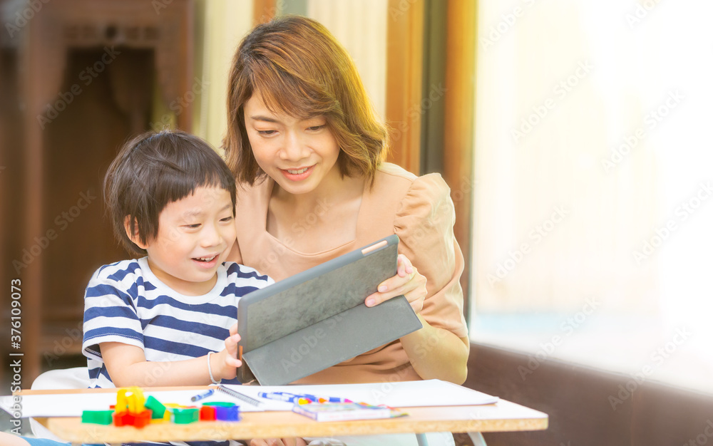 A young boy studies at home with his mom. Home school distance learning and happy learning online education concept A young boy studies at home with his mom. Home school distance learning and happy learning online education concept