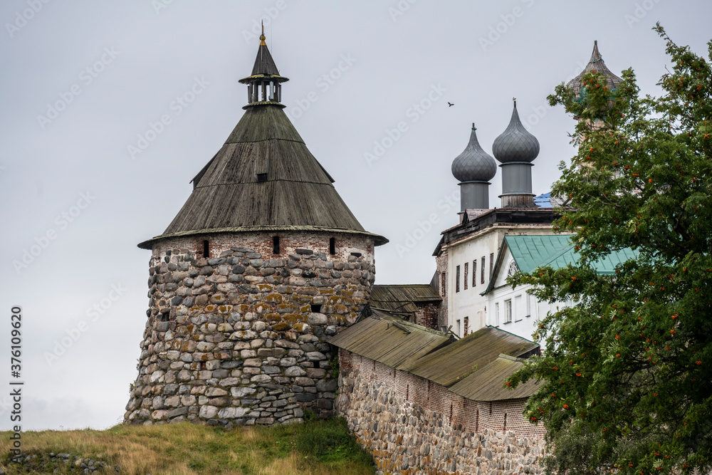 an old stone fortress-monastery with towers and internal buildings against the background of a rainy sky