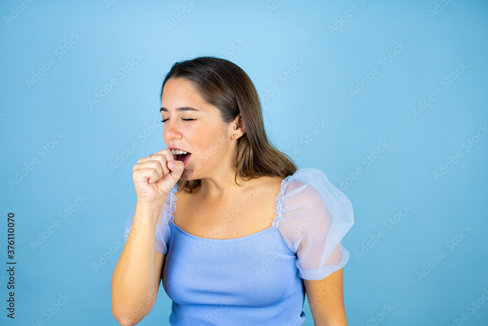 Young beautiful woman over isolated blue background with her hand to her mouth because she's coughing Young beautiful woman over isolated blue background with her hand to her mouth because she's coughing