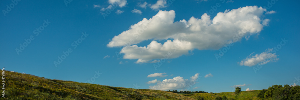 Peaks of hills and white clouds against the blue sky. Web banner. Peaks of hills and white clouds against the blue sky. Web banner.