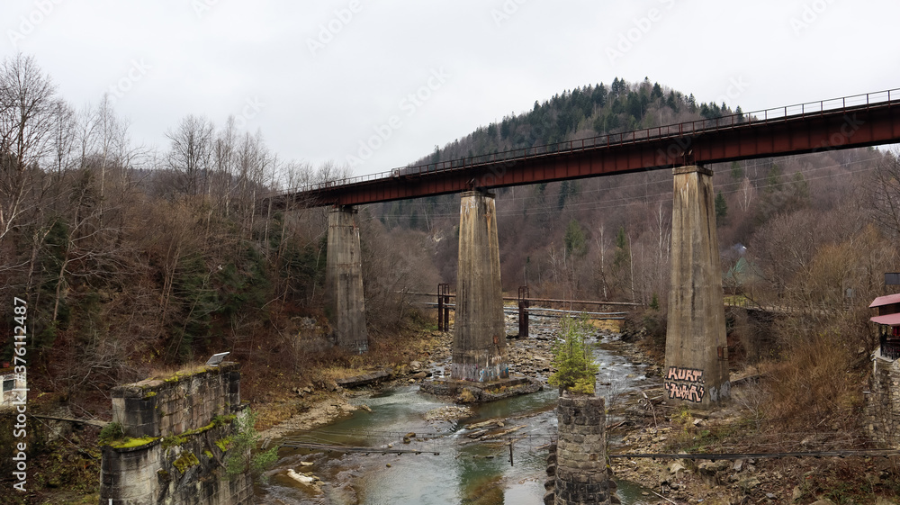 View of the railway bridge over the Prut river. A small town or village of Yaremche among the Carpathians on an autumn afternoon.