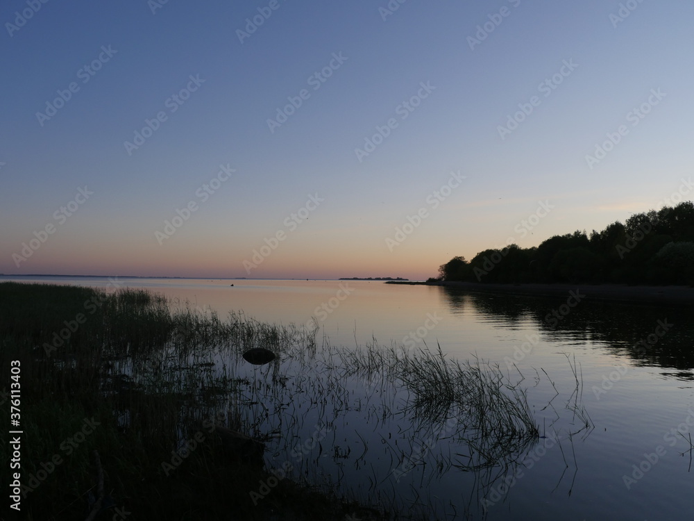 Obraz premium quiet evening on a blue lake, seascape illuminated by the sunset