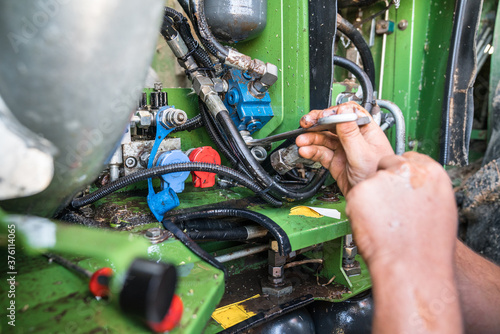 Combine harvester maintenance, repair of hydraulic systems by repairman, mechanisms power transmission of new modern technology combine vehicle motor. Heavy agricultural industry equipment