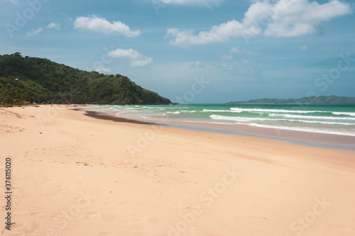 Empty tropical beach on sunny day. Duli beach in Palawan  Philippines. Surf beach. Wide beach with island on background. Travel in Asia. Tropical landscape. Azure water in idyllic lagoon. 