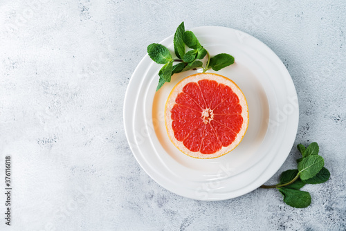 Red grapefruit with slaces and mint leaves on a light background photo