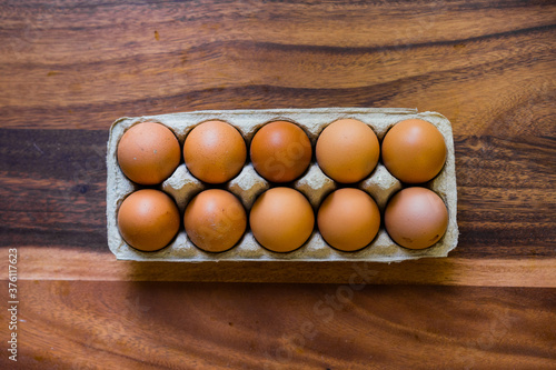 Whole, raw eggs in an egg tray on a wooden kitchen table photo