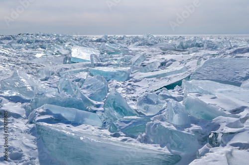 large iridescent crystal white blue ice floes with cracks shine in the light sun, Baikal, endless horizon background