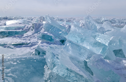 large iridescent crystal blue white ice floes with cracks shine in the light sun, Baikal, endless horizon background