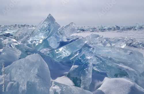 large iridescent crystals white blue ice floes with cracks glow in the light of the sun, lake baikal in winter, horizon, snow winter