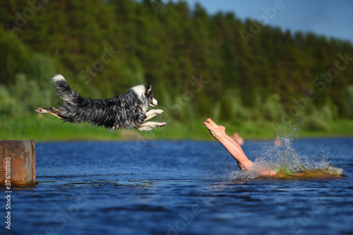 The girl and dog jump together to the water