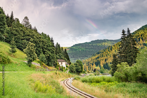 Railway in a scenic valley in the Alps. Part of a rainbow over the mountains. photo