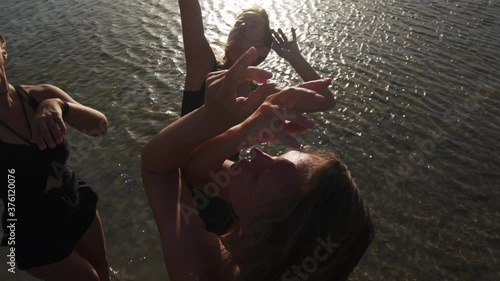 group of young females dancing ecstatic in sea at sunset slow motion photo