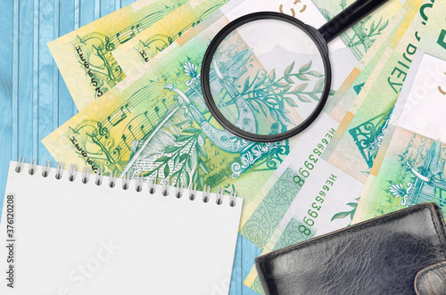 50 Belorussian rubles bills and magnifying glass with black purse and notepad. Concept of counterfeit money. Search for differences in details on money bills to detect fake photo