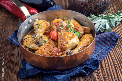 Traditional French coq au vin chicken in sauce offered as close-up in a rustic casserole