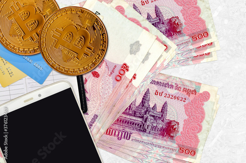 500 Cambodian riels bills and golden bitcoins with smartphone and credit cards. Cryptocurrency investment concept. Crypto mining or trading photo