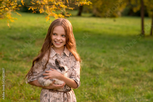 Happy little child girl with cute rabbit. Portrait of kid with pet.