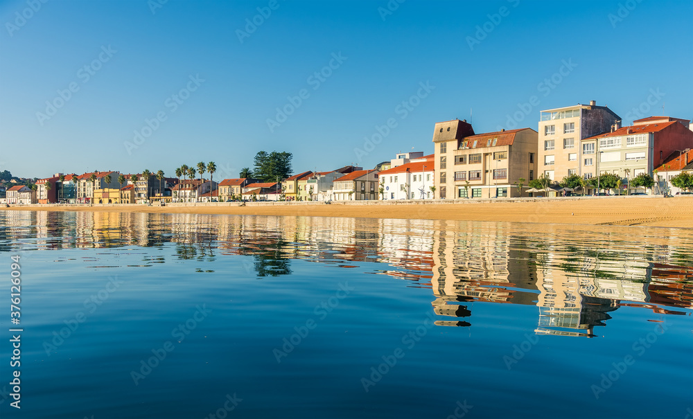 Reflections of buildings in a Galician beach