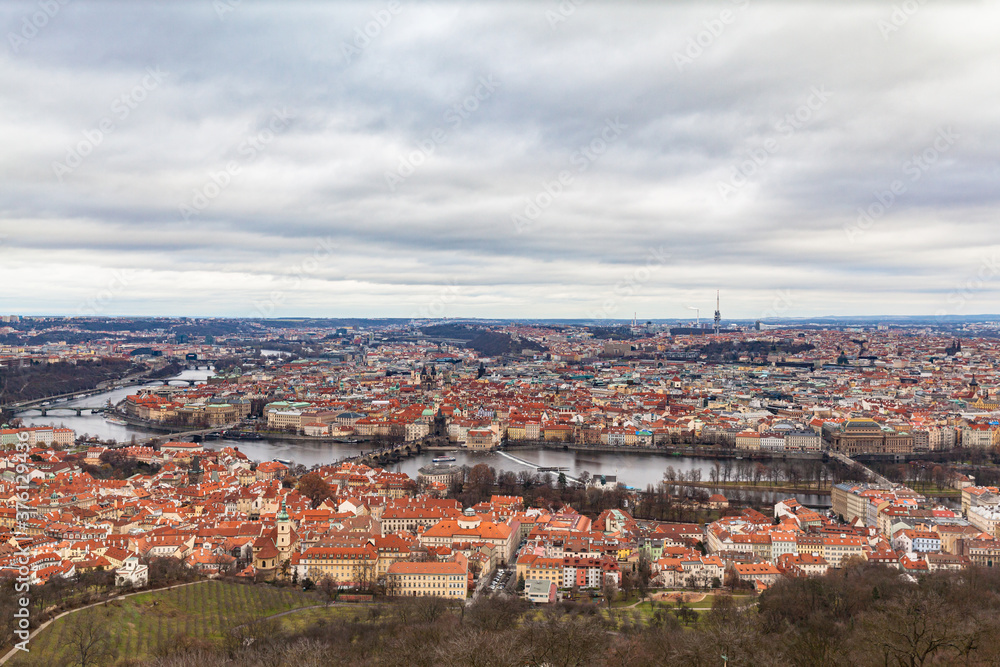 Aerial panorama view of Prague cityscape with many historic buildings and Vltava river flowing through the old town on a cloudy day from top of Petrin Hill, Czech Republic