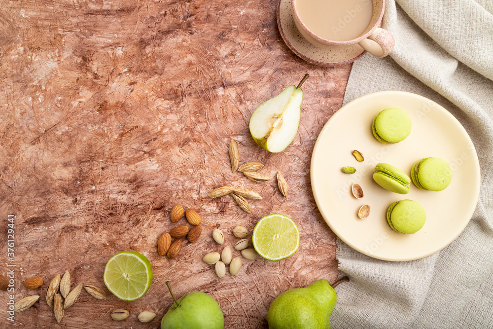 Green macarons or macaroons cakes with cup of coffee on a brown concrete background. Top view, copy space. Green macarons or macaroons cakes with cup of coffee on a brown concrete background. Top view, copy space.
